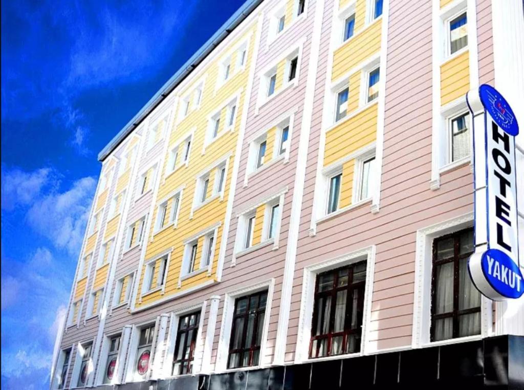 凡城Hotel Yakut的黄色和白色的建筑,前面有标志