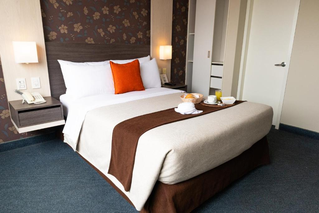 利马圣米格尔帕尔梅托商务酒店的酒店客房配有一张带橙色枕头的大床