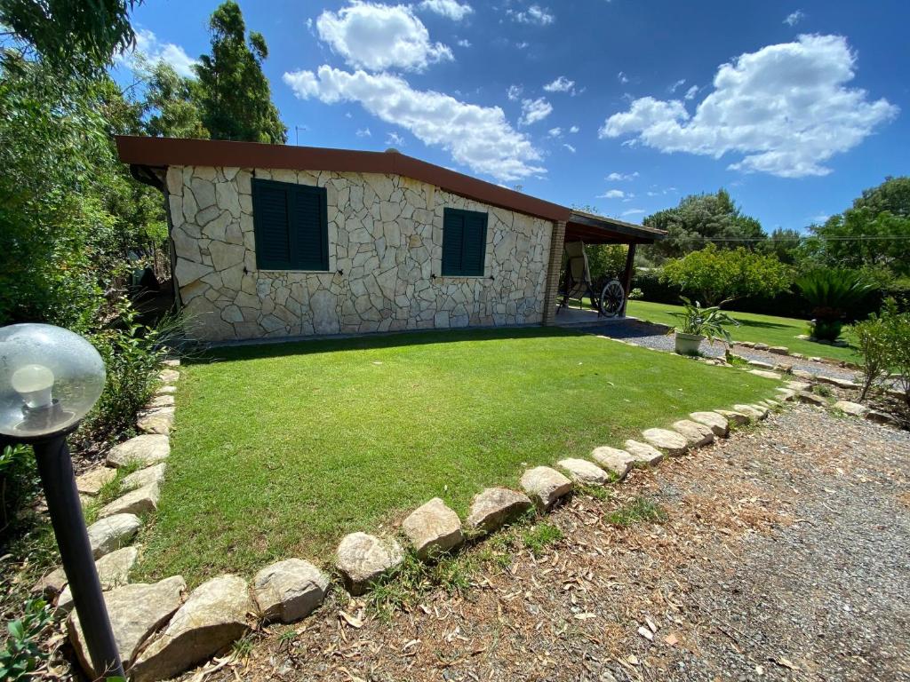 奇亚Casa Chia a 5 minuti dal mare - Su Giudeu Tuerredda的一座石头房子,带草坪的院子