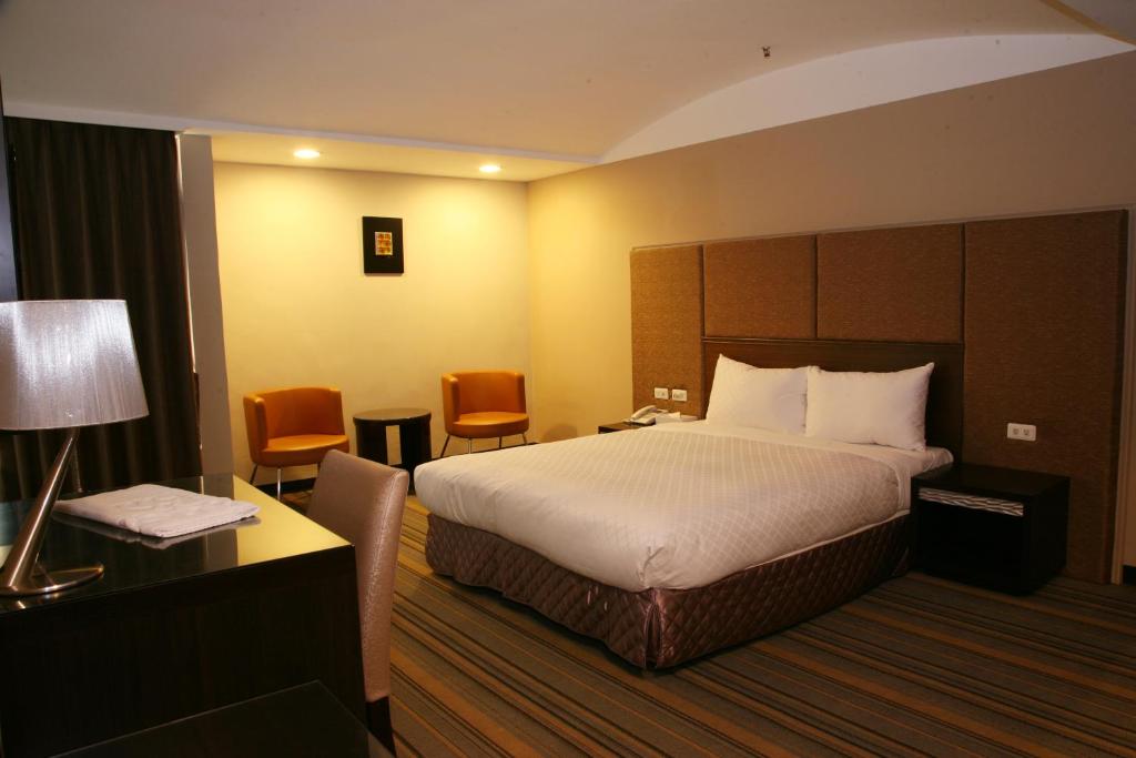 嘉义市嘉义优遊商旅的酒店客房,配有一张床、一张桌子和椅子