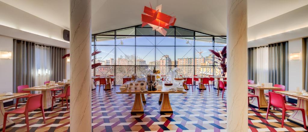 米兰c-hotels Rubens的餐厅设有桌椅和大窗户。