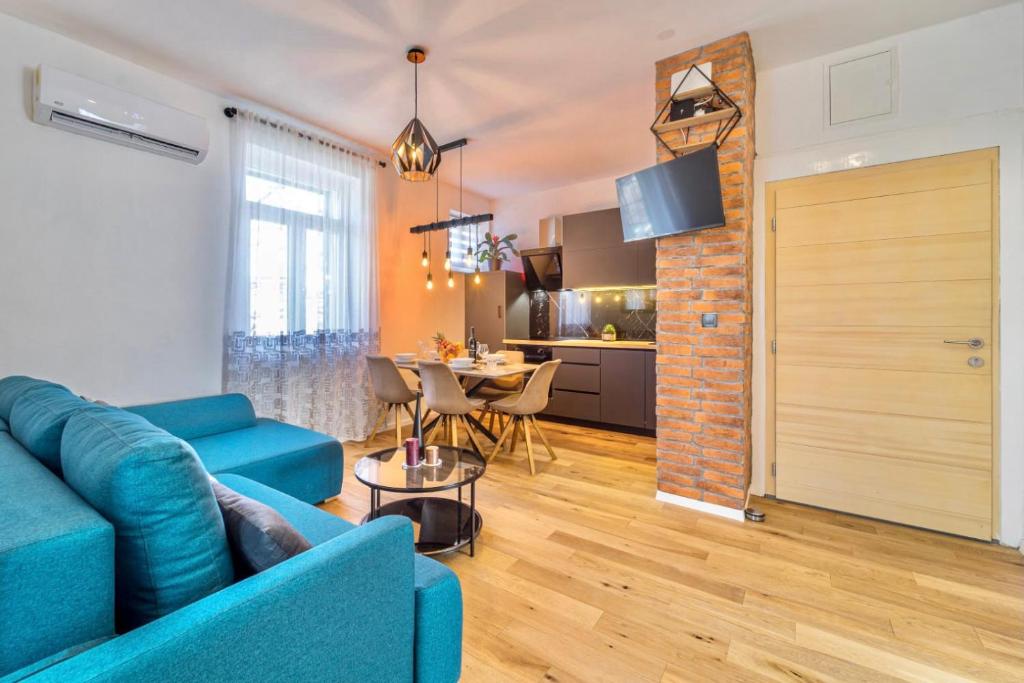 斯普利特Apartman Letifico的一间带蓝色沙发的客厅和一间厨房