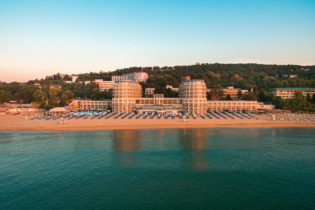 圣君士坦丁和海伦那Azalia Beach Hotel Balneo & SPA的一个带椅子和遮阳伞的海滩和一个度假胜地