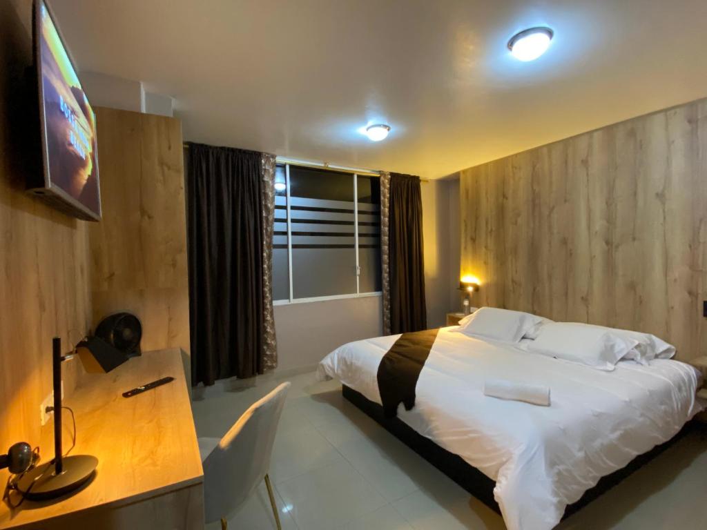 ZamoraHotel Wampushkar的一间卧室配有一张床、一张书桌和一台电视