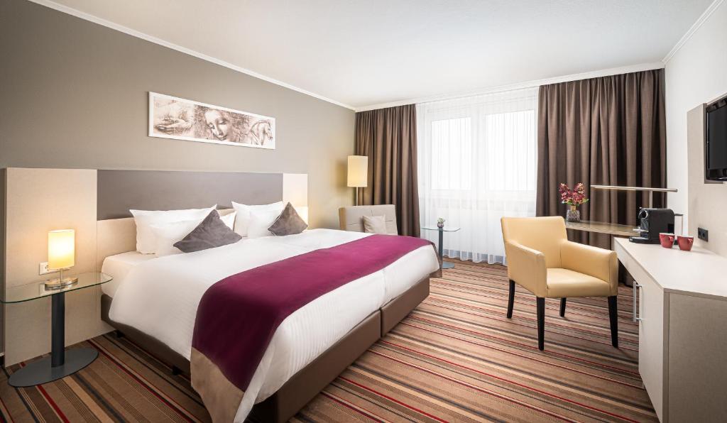 海德堡海德堡市中心莱昂纳多酒店的酒店客房设有一张大床和一张书桌。