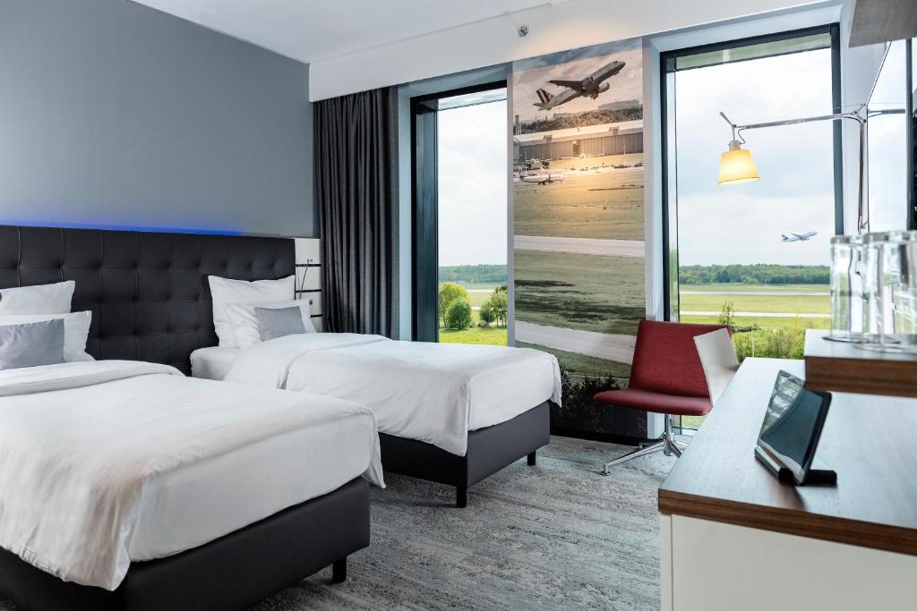 诺德施泰特Airport Plaza Hotel Hamburg的酒店客房设有两张床和窗户。