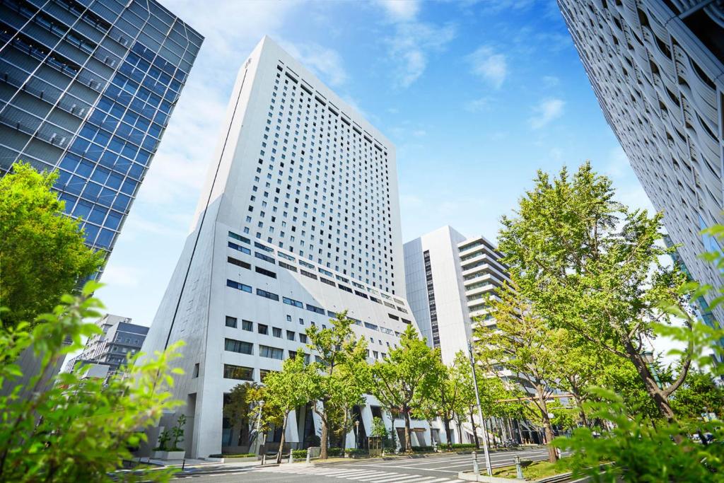 大阪大阪日航国际酒店的一座高大的白色建筑,在城市里,有树木