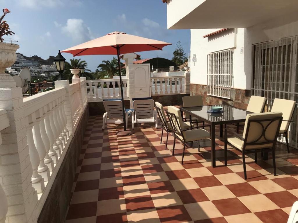 波多黎各Bungalow Isla Margarita的庭院配有桌椅和遮阳伞。