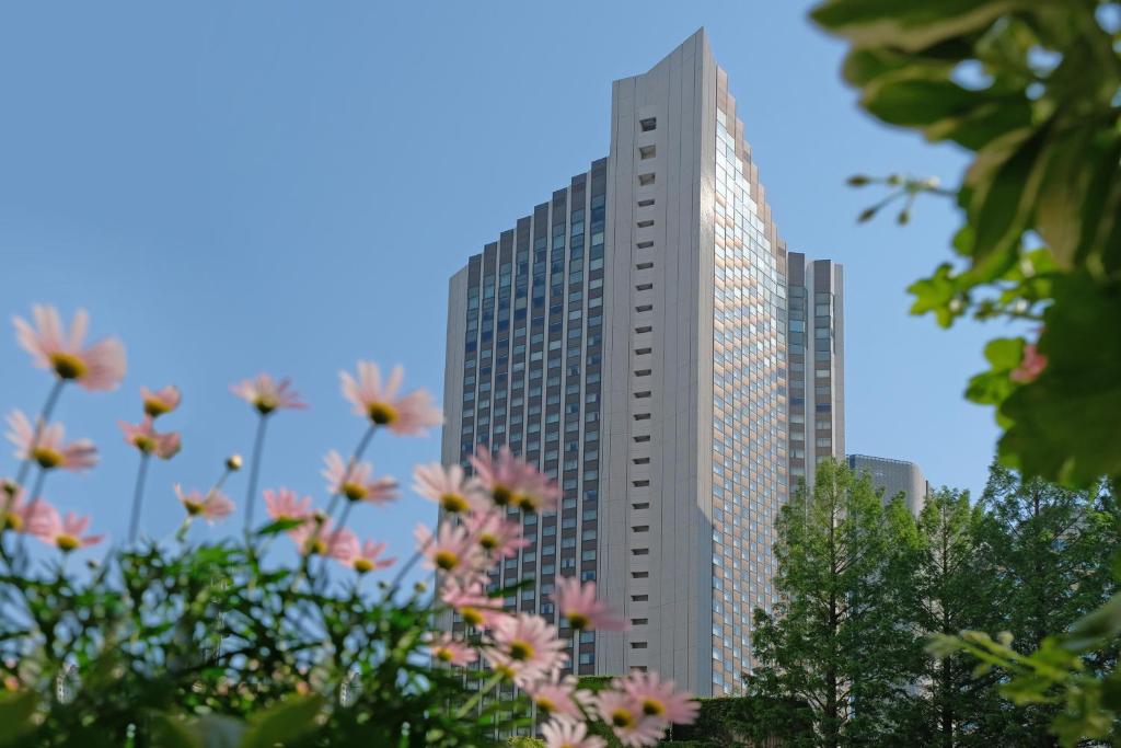 东京东京ANA洲际酒店的一座高大的建筑,前面有粉红色的花朵