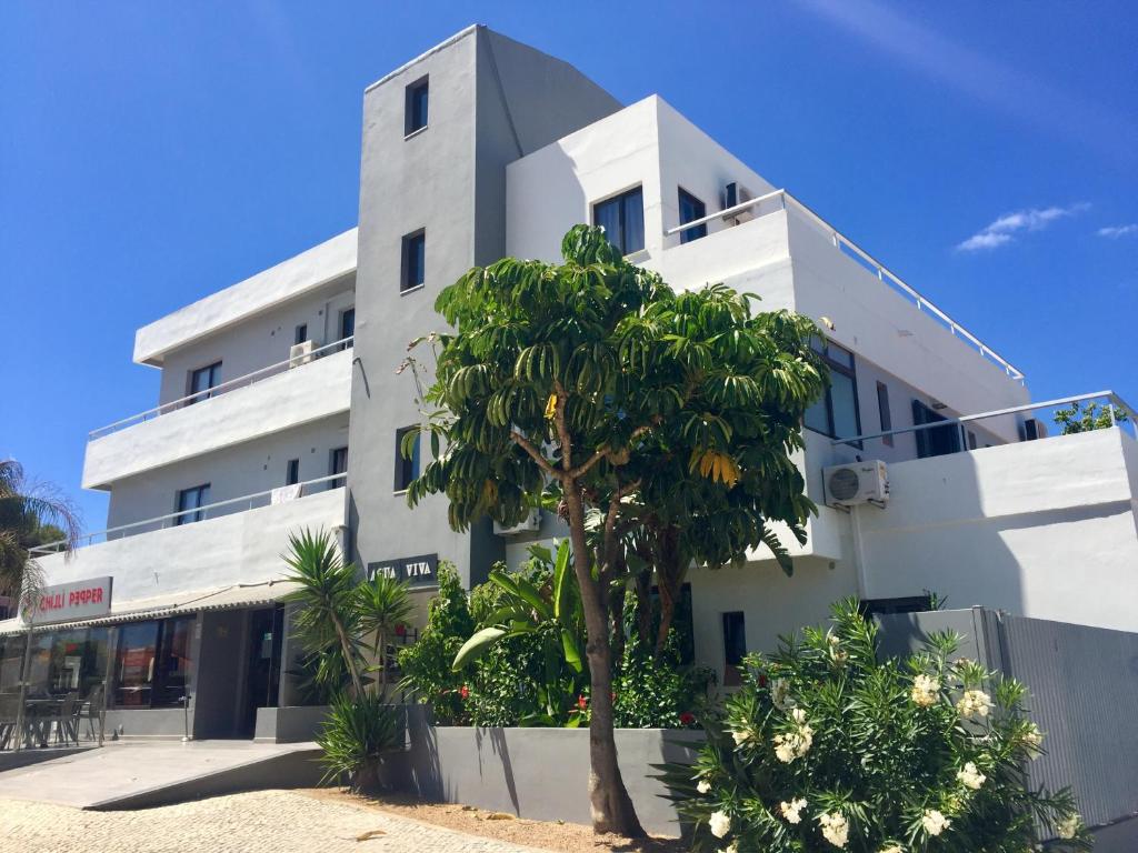 阿尔布费拉阿瓜维瓦公寓的一座白色的建筑,前面有棕榈树