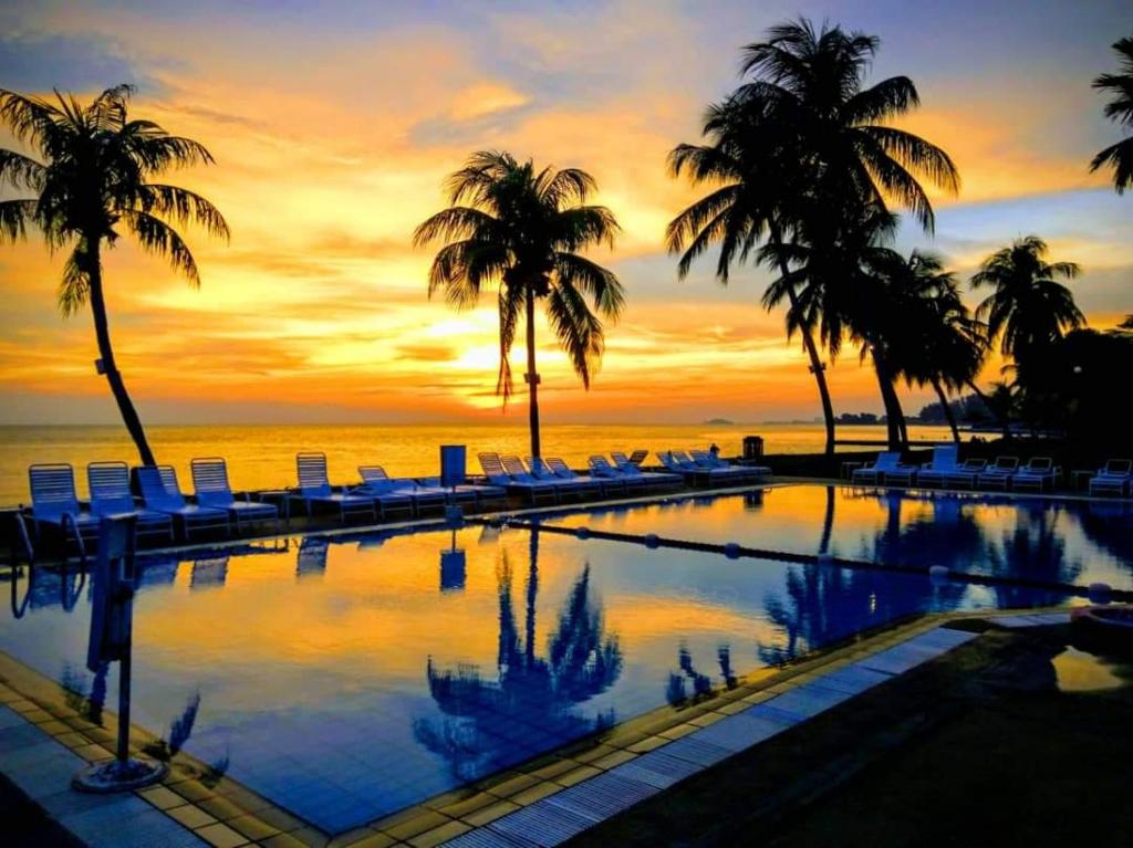Kampong BaharuTanjung Tuan Beach Regency - Hermis Theme的棕榈树和日落的游泳池