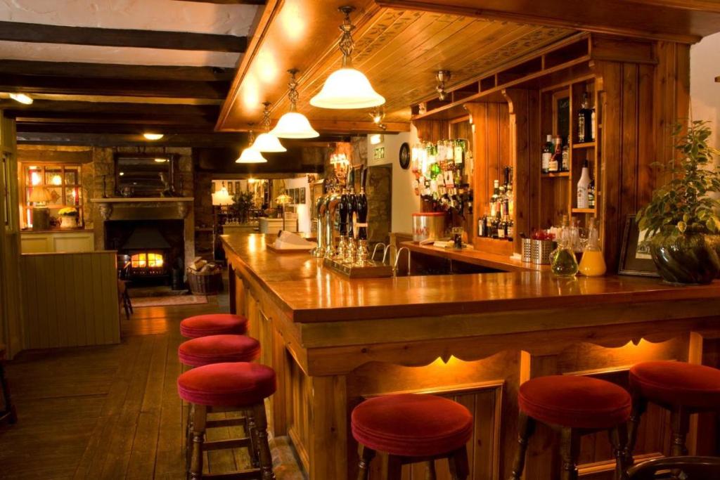 Eglingham坦刻维尔阿姆斯酒店的餐厅内带红色凳子的酒吧