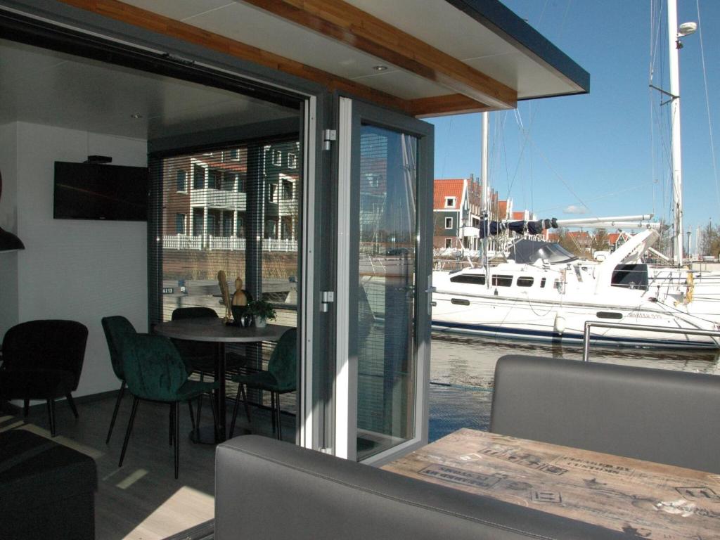 福伦丹Beautiful Houseboat in the harbour of Volendam near Centre的水中带桌子和小船的用餐室