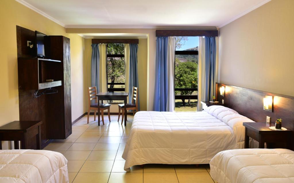 坦迪尔Hotel El Paraiso De La Sierra的酒店客房设有两张床和一张桌子。