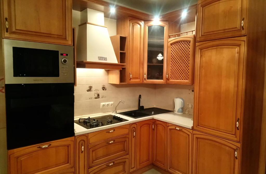 阿拉木图Apartment on Tole Bi的厨房配有木制橱柜和黑色冰箱。