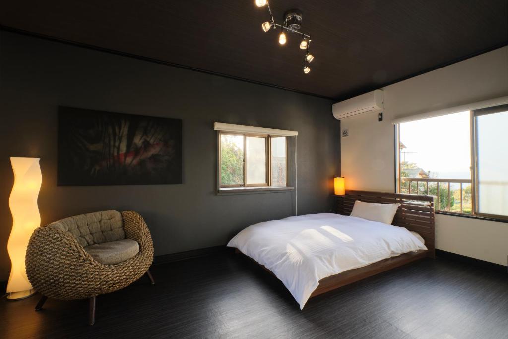 明石市Awaji Aquamarine Resort #1 - Self Check-In Only的卧室配有床、椅子和窗户。