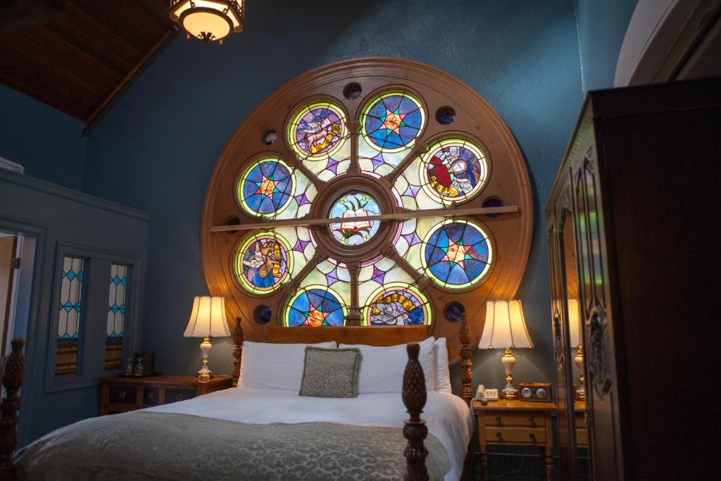 桑威奇钟楼旅馆及小酒馆的一间卧室配有一张带彩色玻璃窗的床