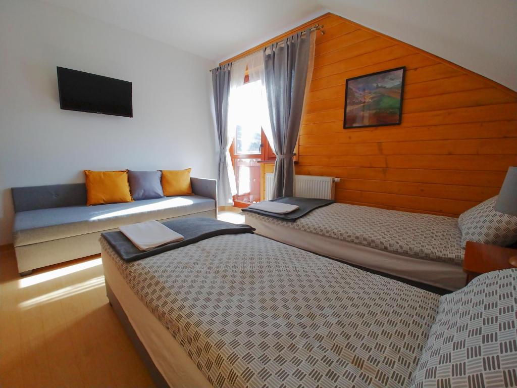 鲁特罗Zajazd PTTK Pod Roztoką的一间卧室设有两张床、一张沙发和一个窗口