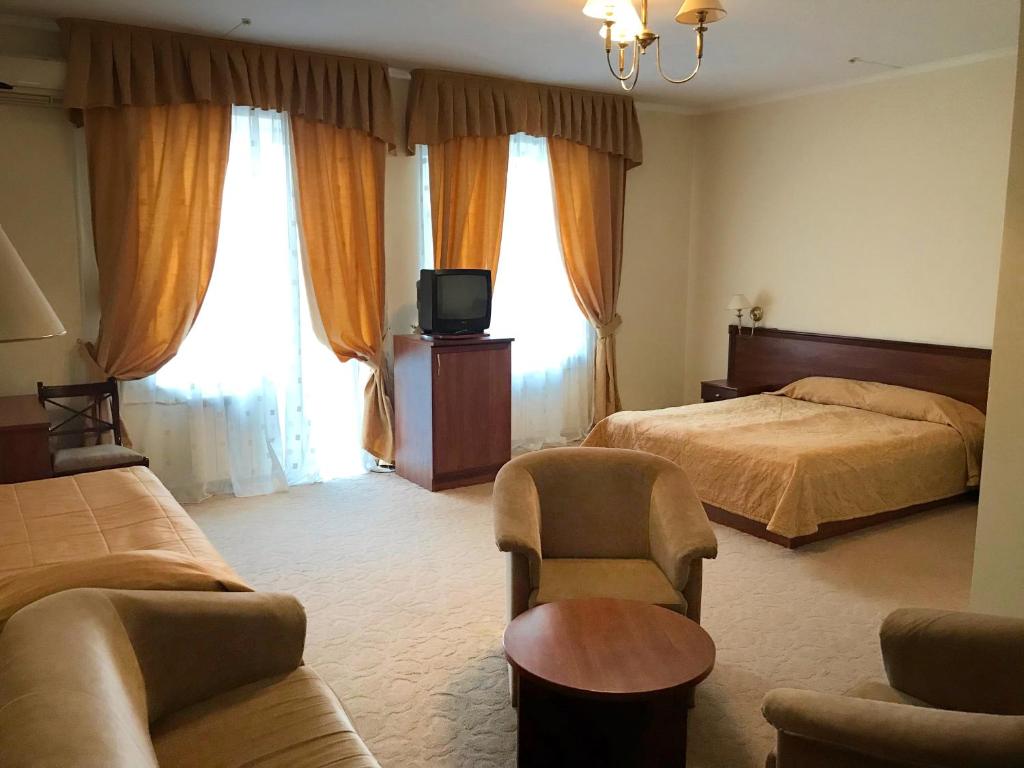 StarovoitoveГотель Ягодин的一间卧室配有一张床、一台电视和一张沙发