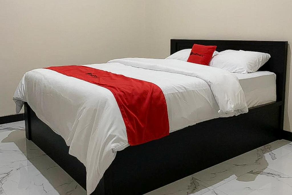 PatiRedDoorz Syariah near Kawasan Simpang Lima Pati的一张带红白毯子和枕头的床