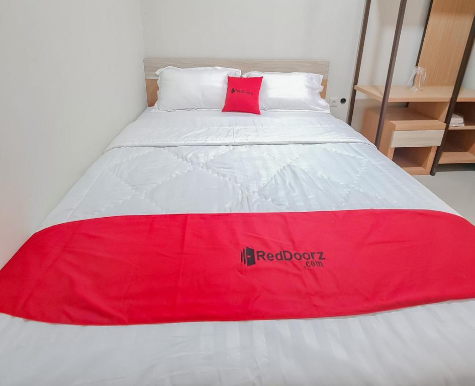 打横RedDoorz Syariah @ Boemi Guesthouse Tasikmalaya的红色和白色的床,上面有红色枕头