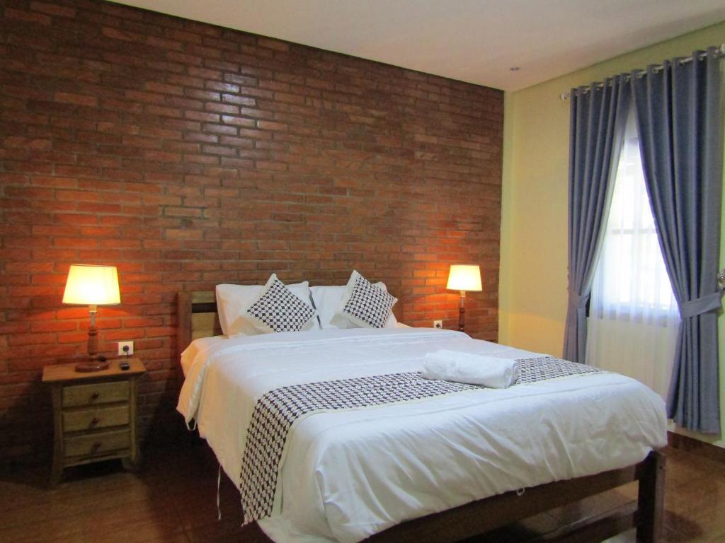 马格朗Nia Maretta House Syariah的一间卧室设有一张大床和砖墙