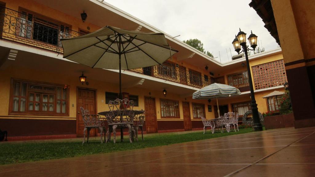 帕茨库卡罗波萨达德拉萨鲁德酒店的大楼前的桌椅和遮阳伞