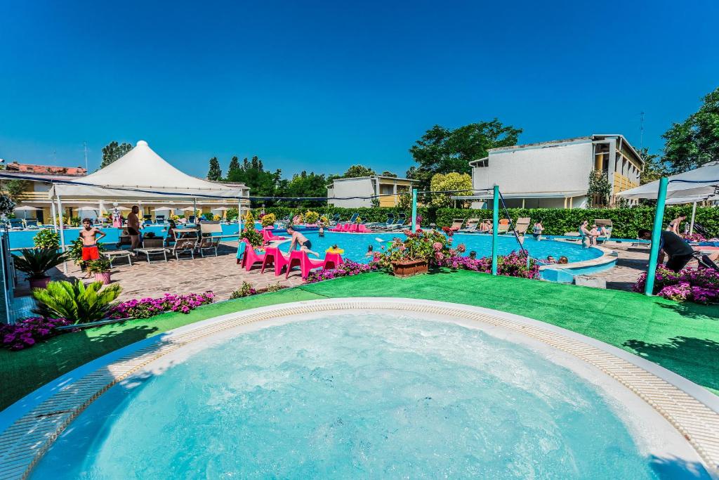 丽都阿德里亚诺Blu Marlin Residence con piscina的一座大型游泳池,那里有人坐在度假村的椅子上