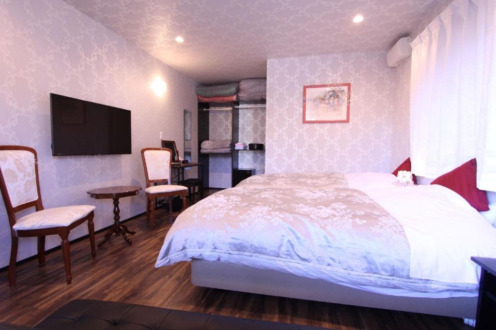 北斗市Yatsugatake Guest House Matsuda House - Vacation STAY 11086的一间卧室配有一张床、一张书桌和一台电视。