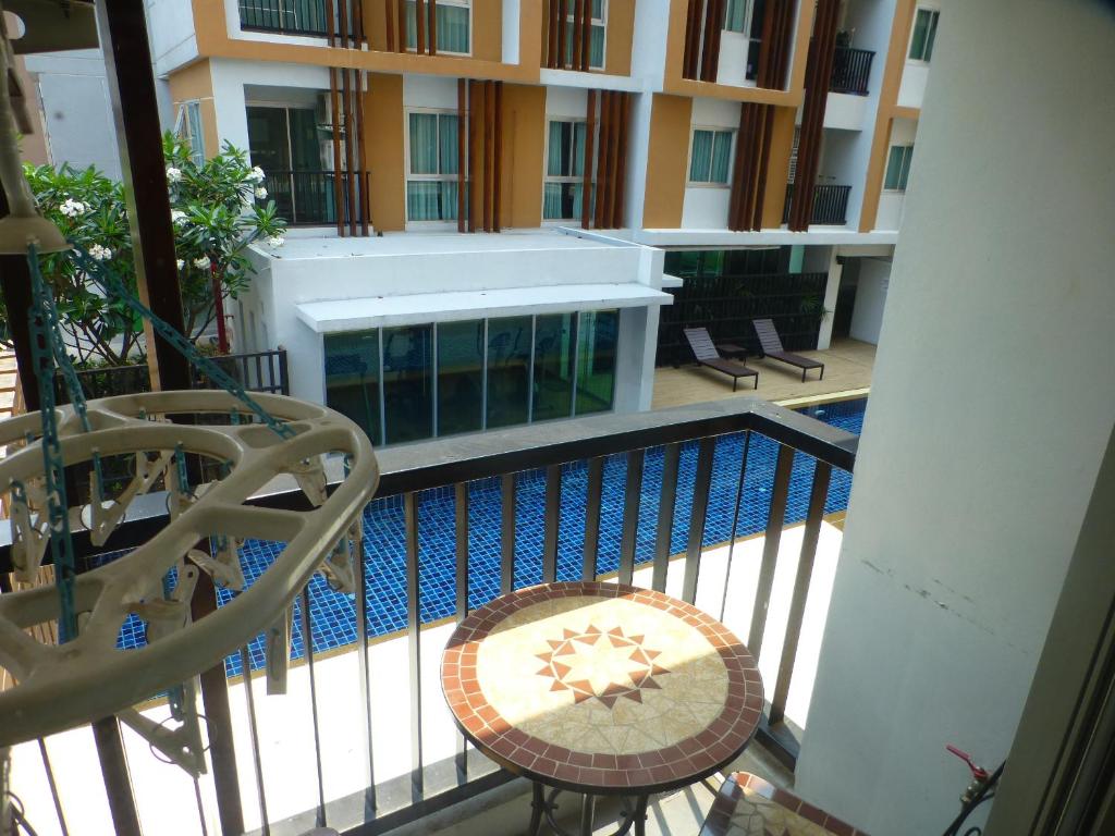 乌隆他尼1 Double bedroom Apartment with Swimming pool security and high speed WiFi的阳台设有游泳池、桌子和椅子。