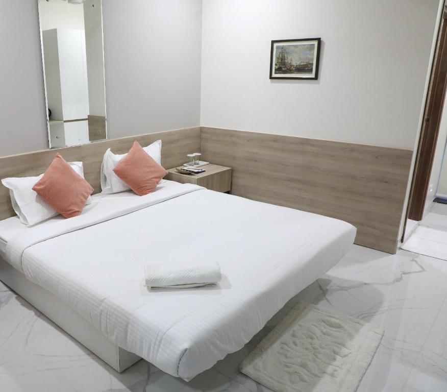 海得拉巴SwanSuites Gachibowli的卧室配有带粉红色枕头的大型白色床
