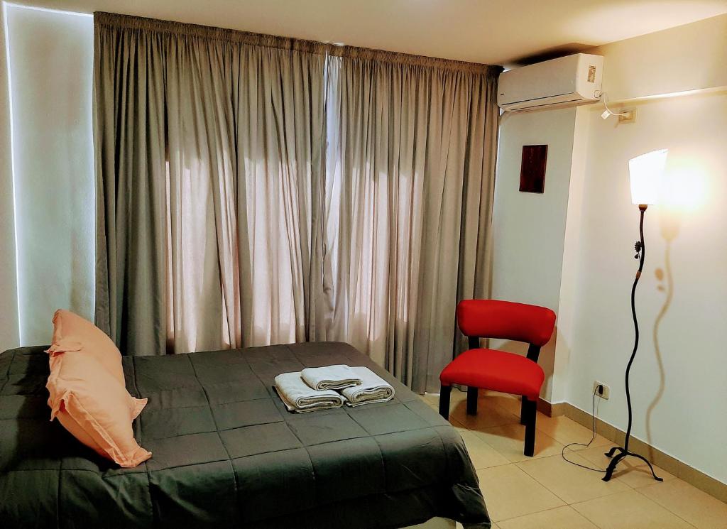罗萨里奥Catamarca Río的一间卧室配有一张床和一张红色椅子