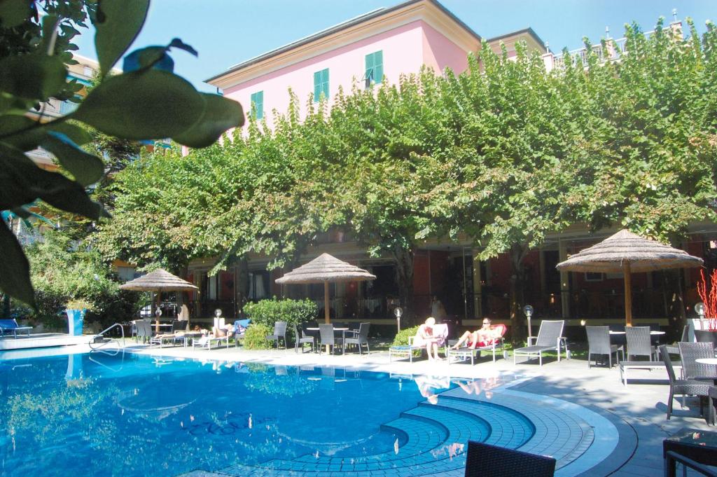 德瓦玛丽娜克蕾丽雅酒店的一座带椅子和遮阳伞的游泳池位于一座建筑旁边