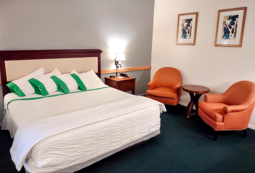 伊纳姆克洛GuestHouse Inn Enumclaw的酒店客房,配有一张床和两张橙色椅子