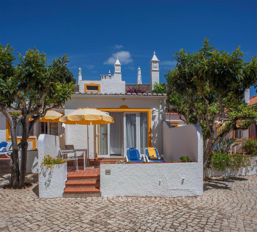 卢斯Quinta Paraiso da Mia - 1 Bedroom Apartment的房屋设有带椅子和遮阳伞的庭院