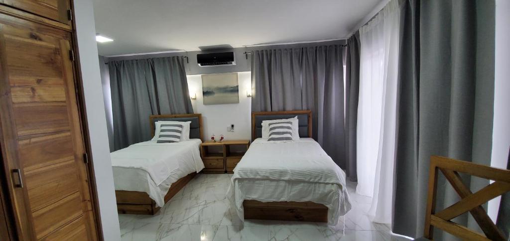 博卡奇卡Boca Grande Hotel Suites的一间卧室设有两张床,窗户配有窗帘