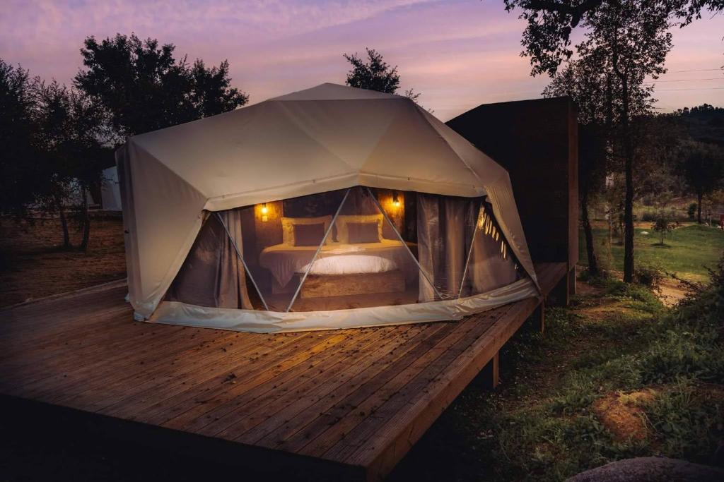 加维昂Gavião Nature Village的木制甲板上的帐篷,配有一张床