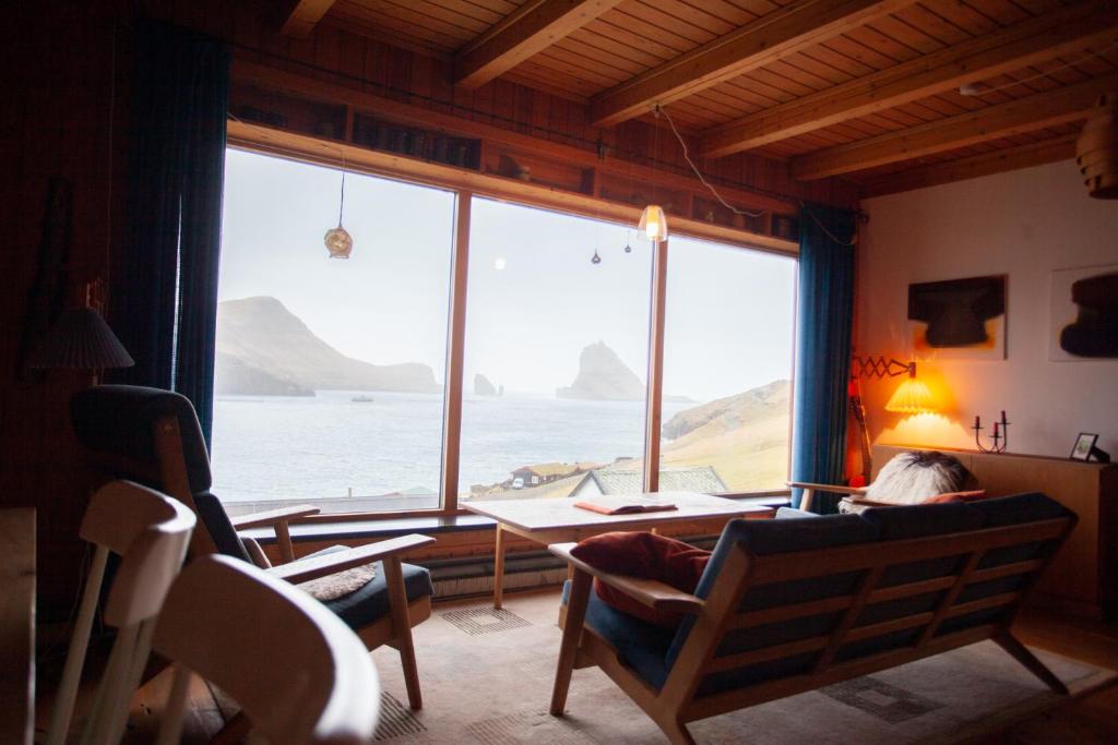 BøurIdyllic Vacation Home with a Breathtaking View的坐在一张桌子上的人,坐在一个有大窗户的房间