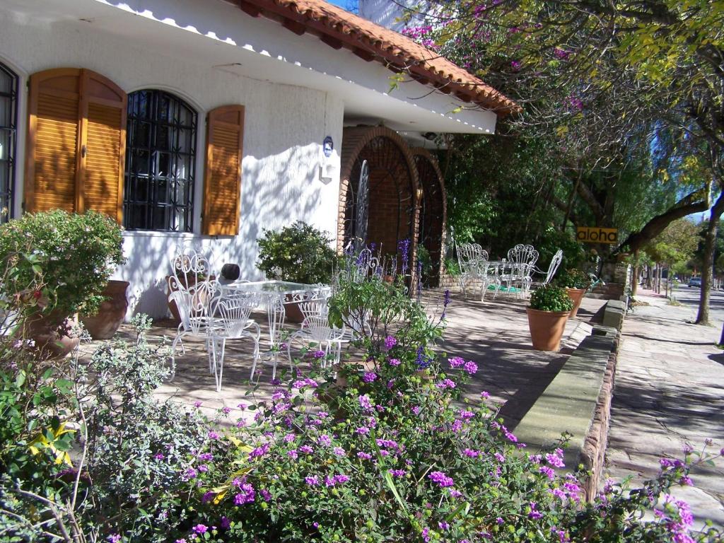 维拉卡洛斯帕兹阿罗哈宾馆的房屋前方带椅子和鲜花的庭院