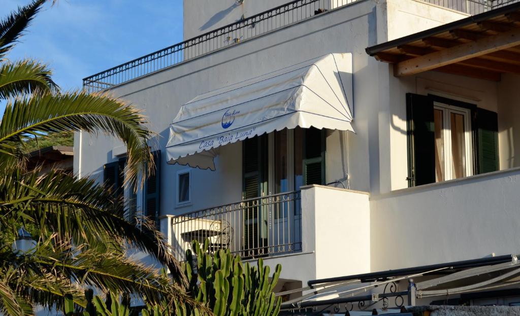 蓬扎Casa Baia Luna的带阳台的白色建筑和棕榈树