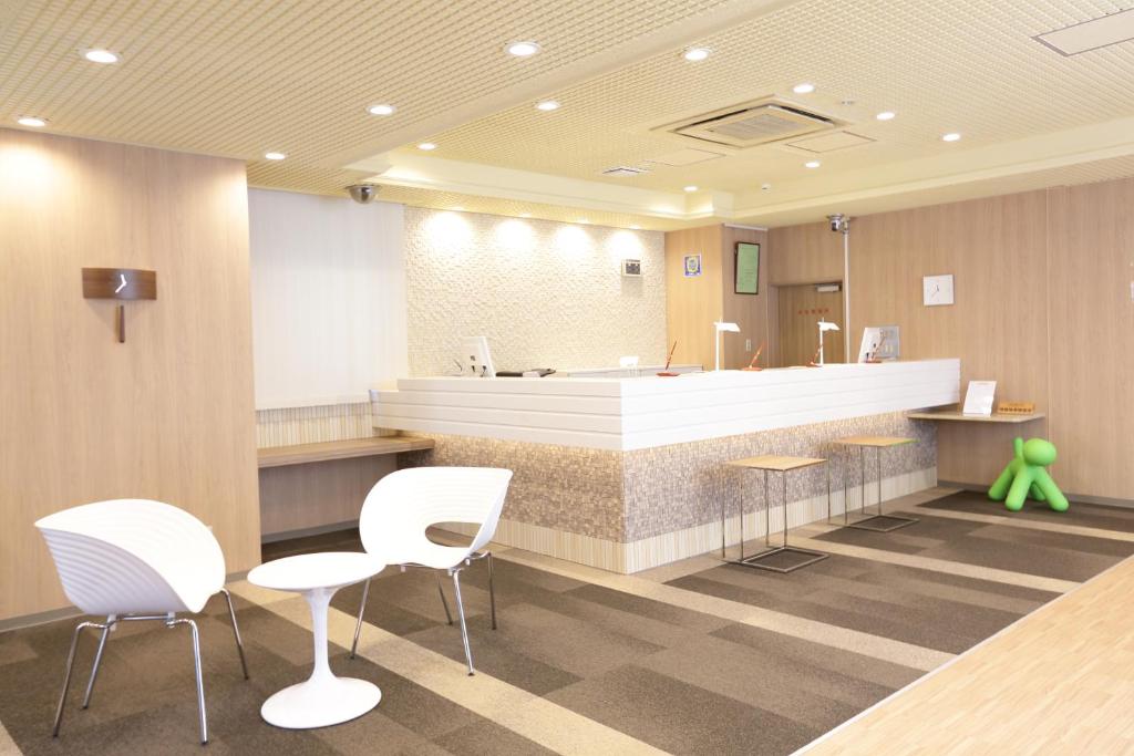 仙台绿色标志酒店的一间设有白色椅子和前台柜台的等候室