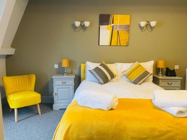 韦德布里奇The Swan Hotel的一间卧室配有黄色的床和黄色的椅子