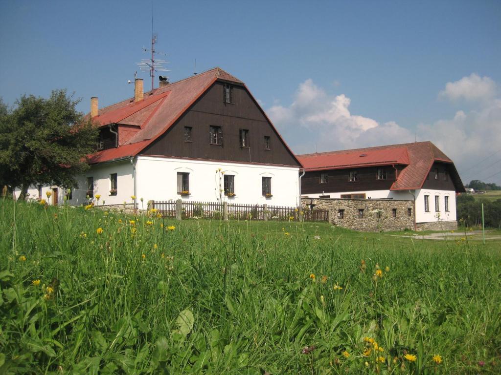 ZdíkovBaurů Dvůr的一座白色的大建筑,在田野上设有红色屋顶