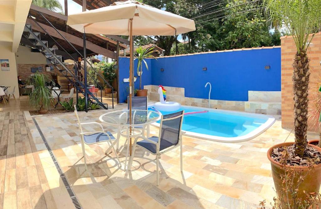 伊利亚贝拉VELINN Pousada Praia do Perequê的一个带桌子和遮阳伞的庭院和一个游泳池