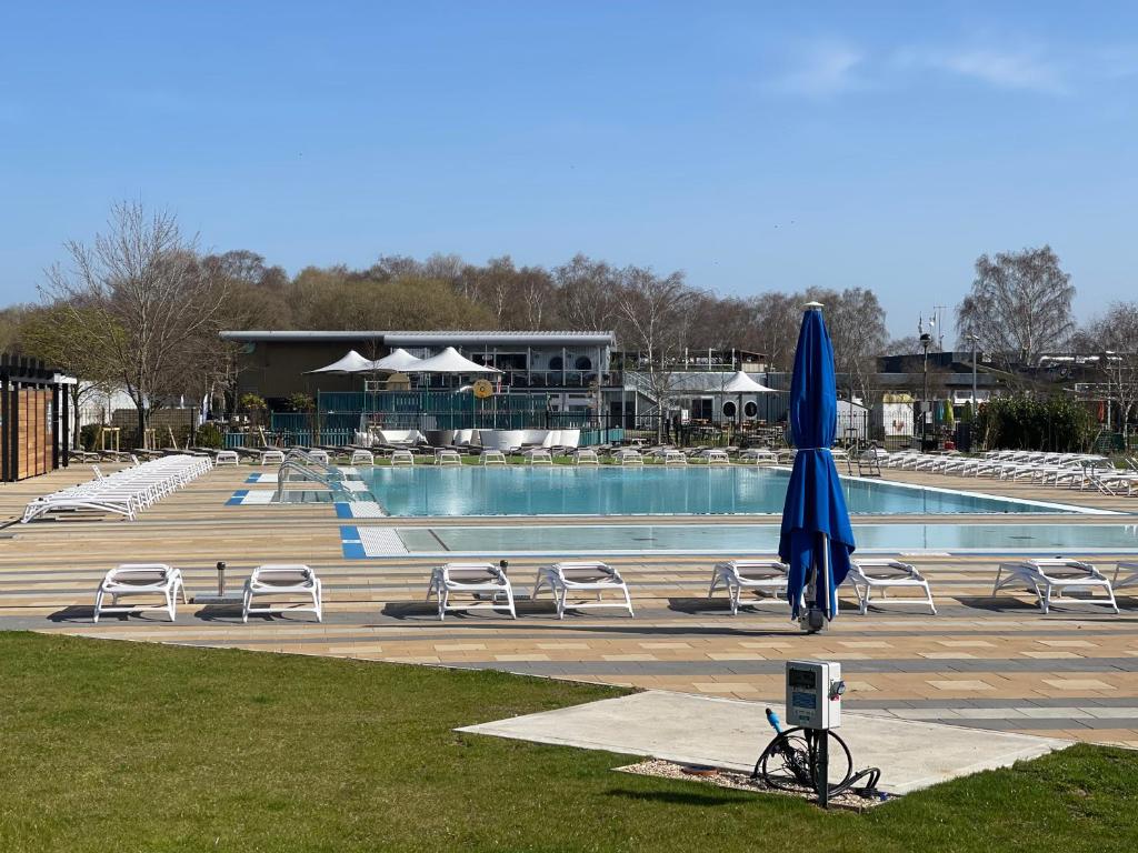 林肯Holiday Home Breaks At Tattershall Lakes的一个带椅子和蓝伞的游泳池