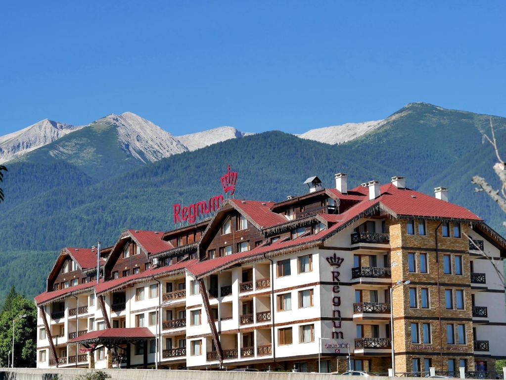 班斯科Regnum Bansko Ski Hotel & SPA的酒店大楼的背景是群山
