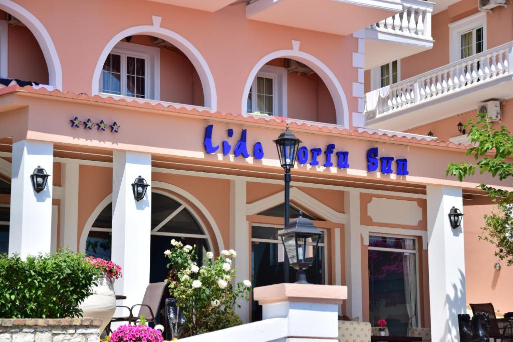 贝尼蔡斯Lido Corfu Sun Hotel 4 Stars All-inclusive的粉红色的建筑,上面标有读罗尼卡沙尔的标志
