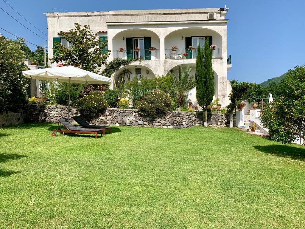伊斯基亚Villa Vincenzo Di Meglio的一个带长凳和遮阳伞的草坪的房子