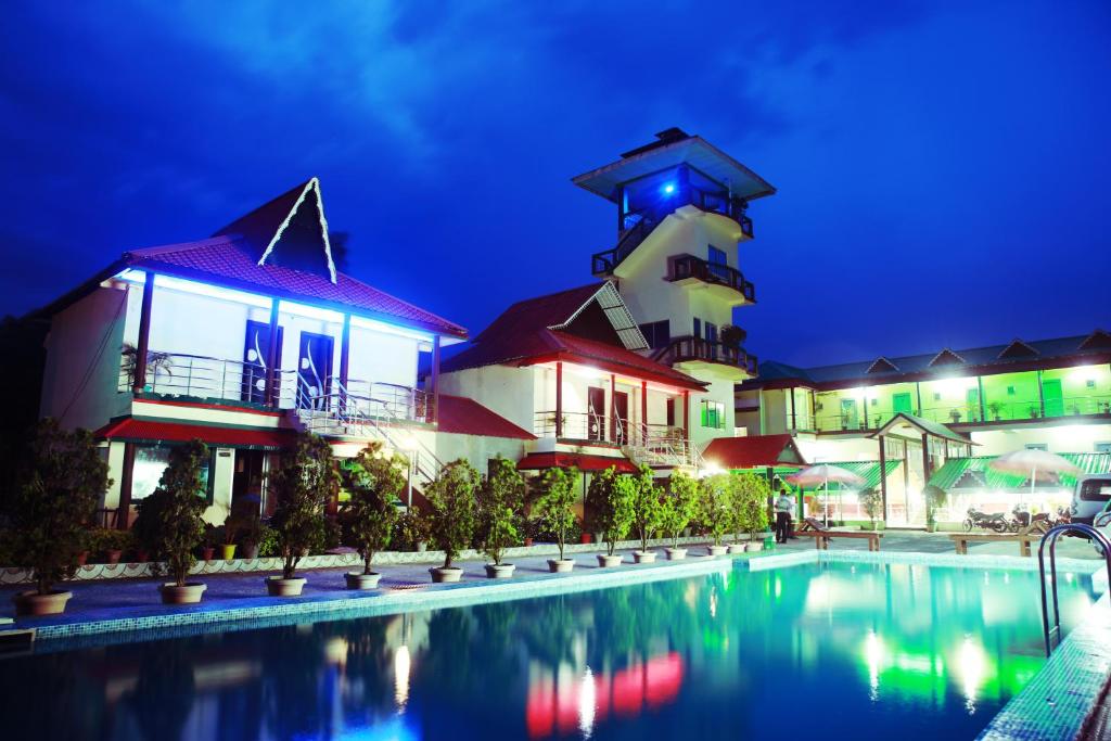 Alīpur DuārMaa Greenary View - A Holiday Resort的夜间带游泳池和灯塔的度假胜地