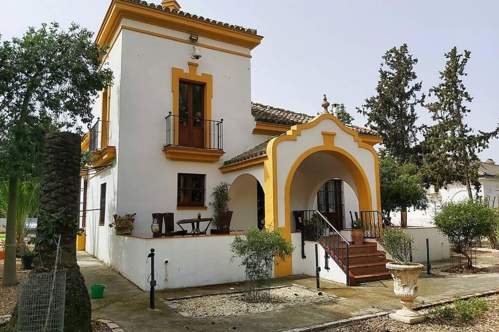 塞维利亚Cortijo San José的白色和黄色的房子,设有门廊和楼梯